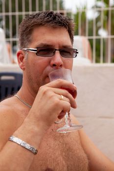 Relaxation; man is drinking rosé wine on vacation