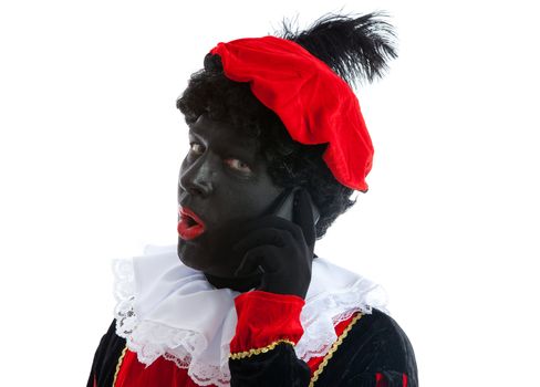 Zwarte piet ( black pete) typical Dutch character part of a traditional event celebrating the birthday of Sinterklaas in december over white background with mobile phone