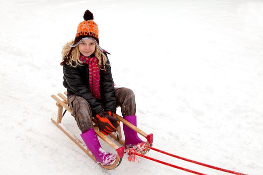 Girl on sled in the snow looking into camera