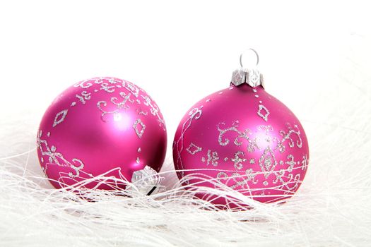Two pink christmas balls with silver glitters over white background