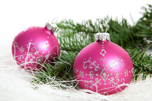 Two pink christmas balls with silver glitters over white background