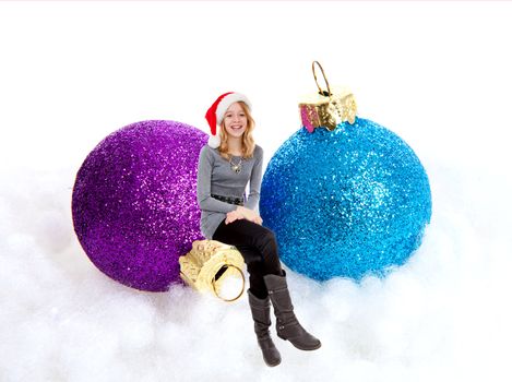Girl sitting on Christmas balls over white background