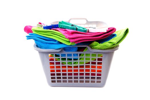 Laundry basket filled with colorful towels and pegs over white background