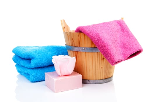 wooden bucket for spa or sauna with colorful towels and soap over white background