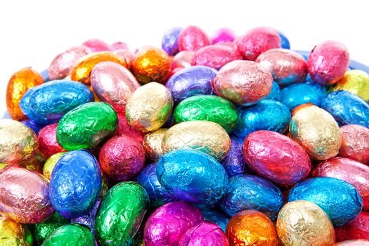 Pile of colorful easter eggs in closeup over white background