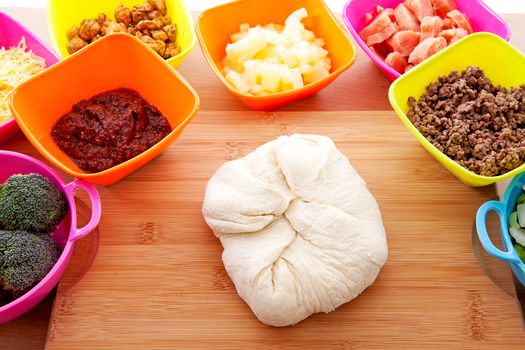 Making pizza: ingredients and pasta dough on wooden cutting board