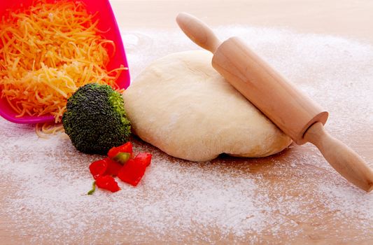 Making pizza: ingredients and pasta dough on wooden cutting board 