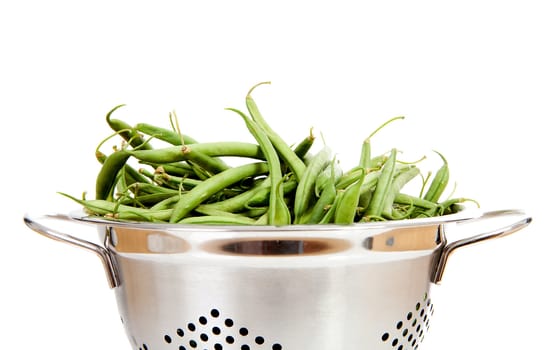 Metal colander with long green beans over white background