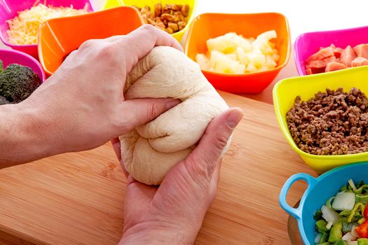 Making pizza: ingredients and hands with pasta dough on wooden cutting board
