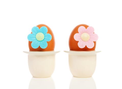 Two chicken eggs in holder with flowers over white background