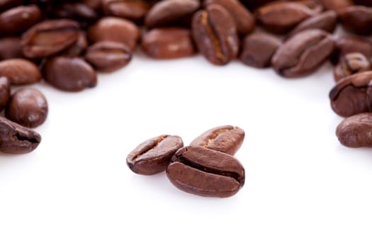 Roasted coffee beans in closeup over white 
