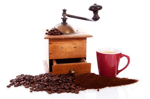 Old wooden coffee grinder with beans and cup over white background
