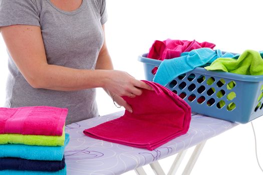 Housewife is folding colorful towels in closeup over white background