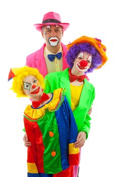 Three people dressed up as colorful funny clowns over white background