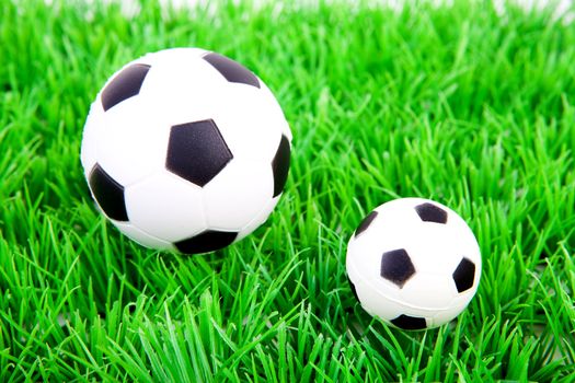 One big and one little soccer ball on plastic grass 