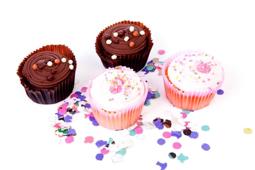 Four delicious cupcakes and colorful confetti over white background