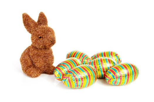 Easter bunny and colorful chocolate easter eggs over white background
