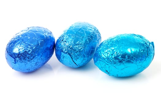 Three blue chocolate easter eggs over white background