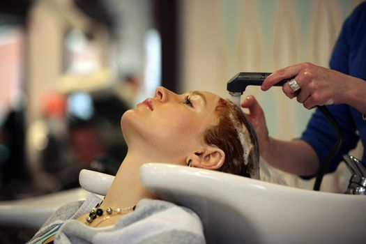 Barber makes a hair-dress to the young brunette