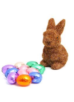 Brown easter bunny and colorful chocolate eggs over white background