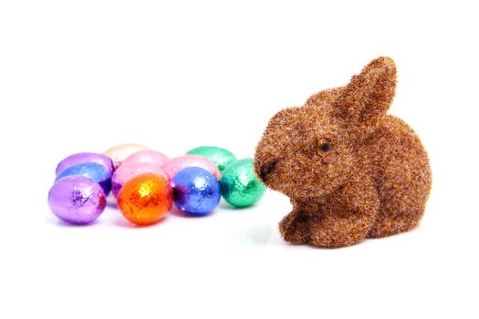 Brown easter bunny and colorful chocolate eggs over white background