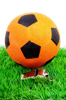 Orange soccer ball and flute on grass over white background