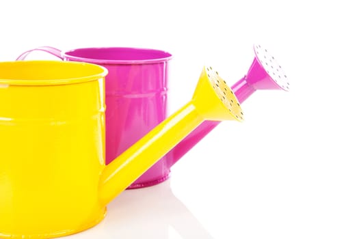 Pink and yellow watering can over white background