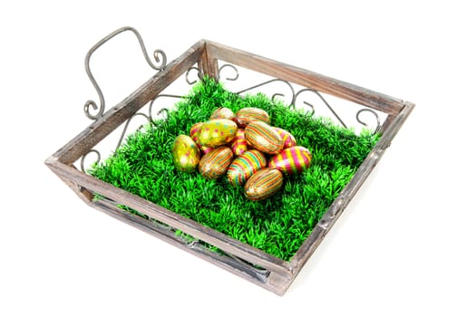 Wooden tray with grass and easter eggs over white background