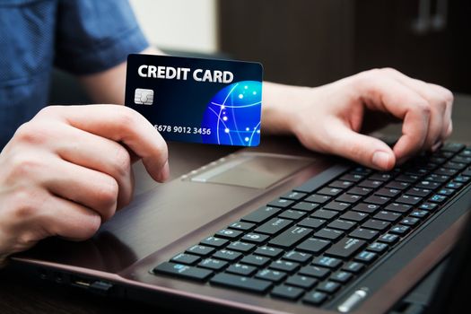 Man holding colorful credit card. Hands on computer keyboard