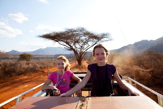 Going on safari: two girls standing on top of jeep
