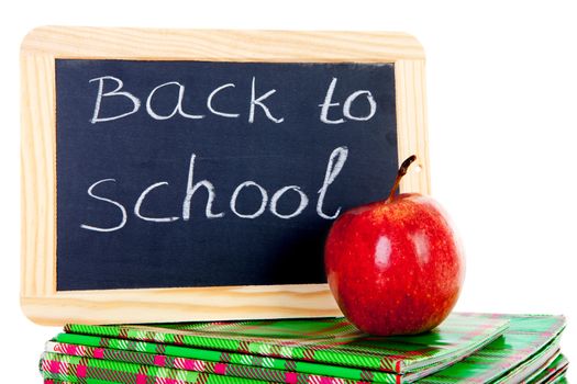 back to school: blackboard slate and stack of books with apple on top over white background 

