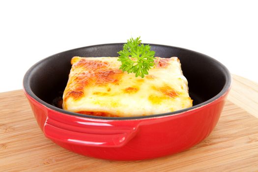 fresh Lasagna dinner in pan on wooden cutting board over white background
