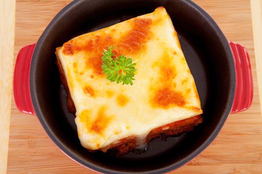 Lasagna dinner in pan on wooden cutting board