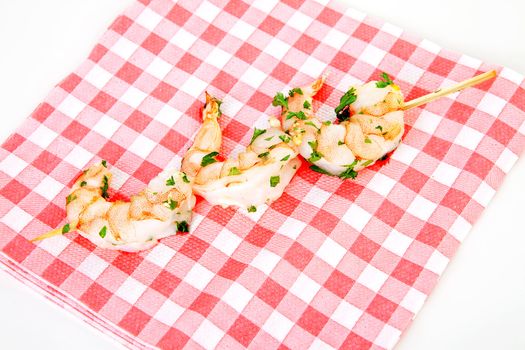 Little prawn snacks on checkered napkin over white backgorund