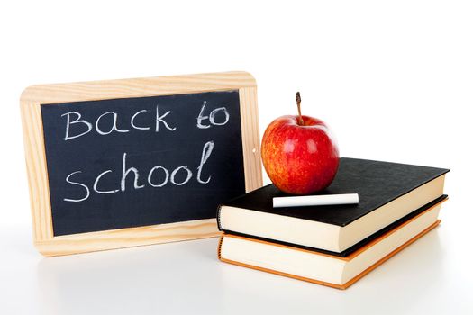 back to school: blackboard slate and stack of books with apple on top over white background 
