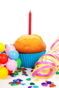Birthday cupcake with candle, party streamers and colorful confetti over white background