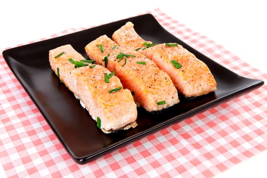 Plate with fresh salmon on checkered napkin over white background