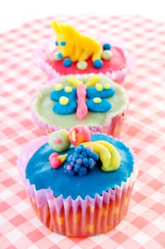 three cupcakes with marzipan decoration on napkin