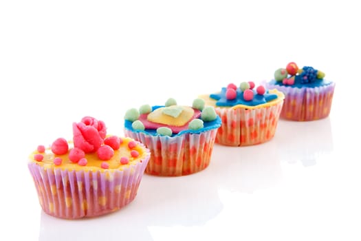 Row cupcakes with colorful marzipan decoration over white background