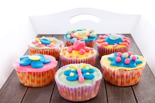 Tray with seven delicious decorated colorful cupcakes