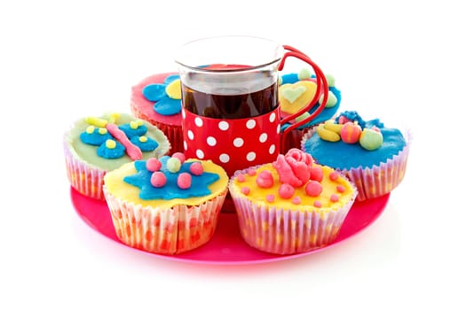 Pink plate with cup of tea and cupcakes over white background