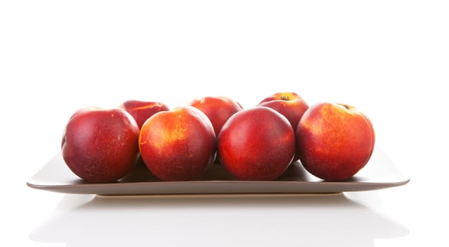 Plate with fresh nectarines over white background