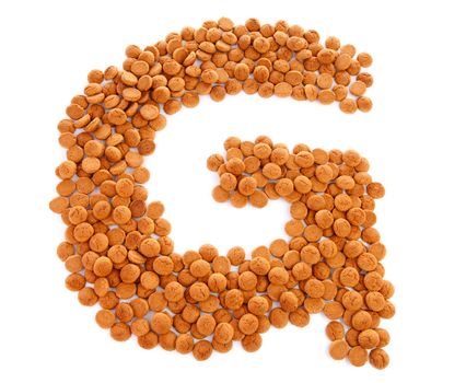 Ginger nuts, pepernoten, in the shape of letter G isolated on white background. Typical Dutch candy for Sinterklaas event in december