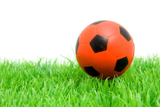 Orange soccer ball on grass over white background