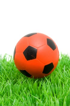 Orange soccer ball on grass over white background