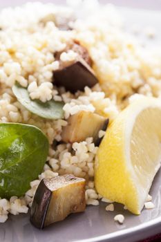 Bulgur salad with spinach roasted eggplant and a lemon wedge