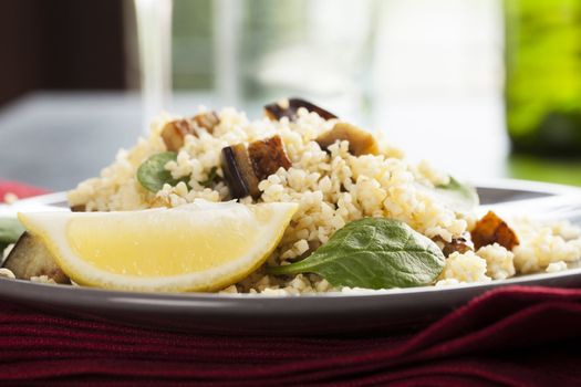 Bulgur salad with spinach roasted eggplant and a lemon wedge