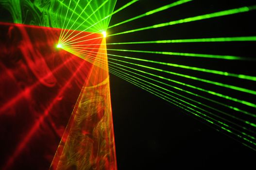 Colour lasers in smoke on a black background.