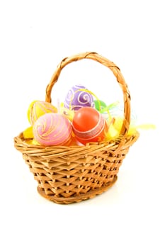 Cane basket with colorful easter eggs over white background