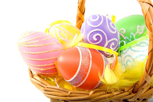 Cane basket with colorful easter eggs over white background